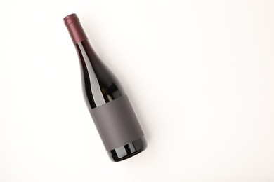Bottle of tasty red wine on white background, top view. Space for text