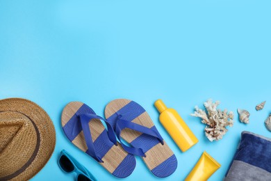 Photo of Stylish flip flops and beach objects on light blue background, flat lay. Space for text