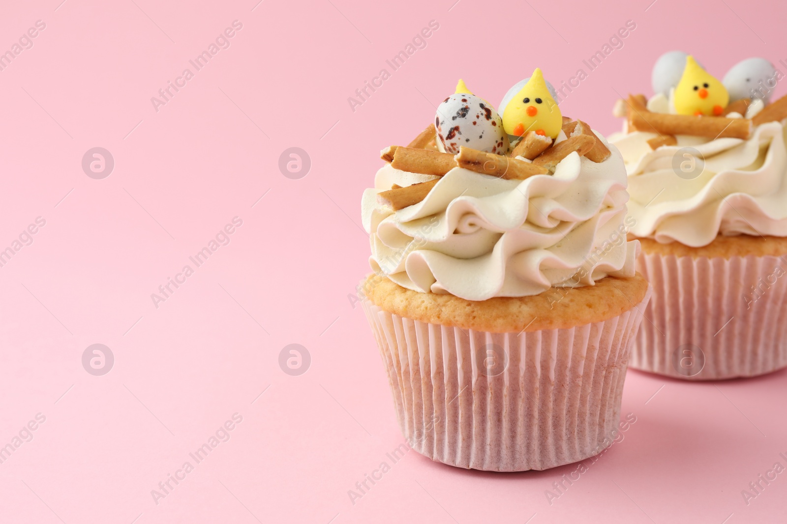 Photo of Tasty Easter cupcakes with vanilla cream on pink background, space for text