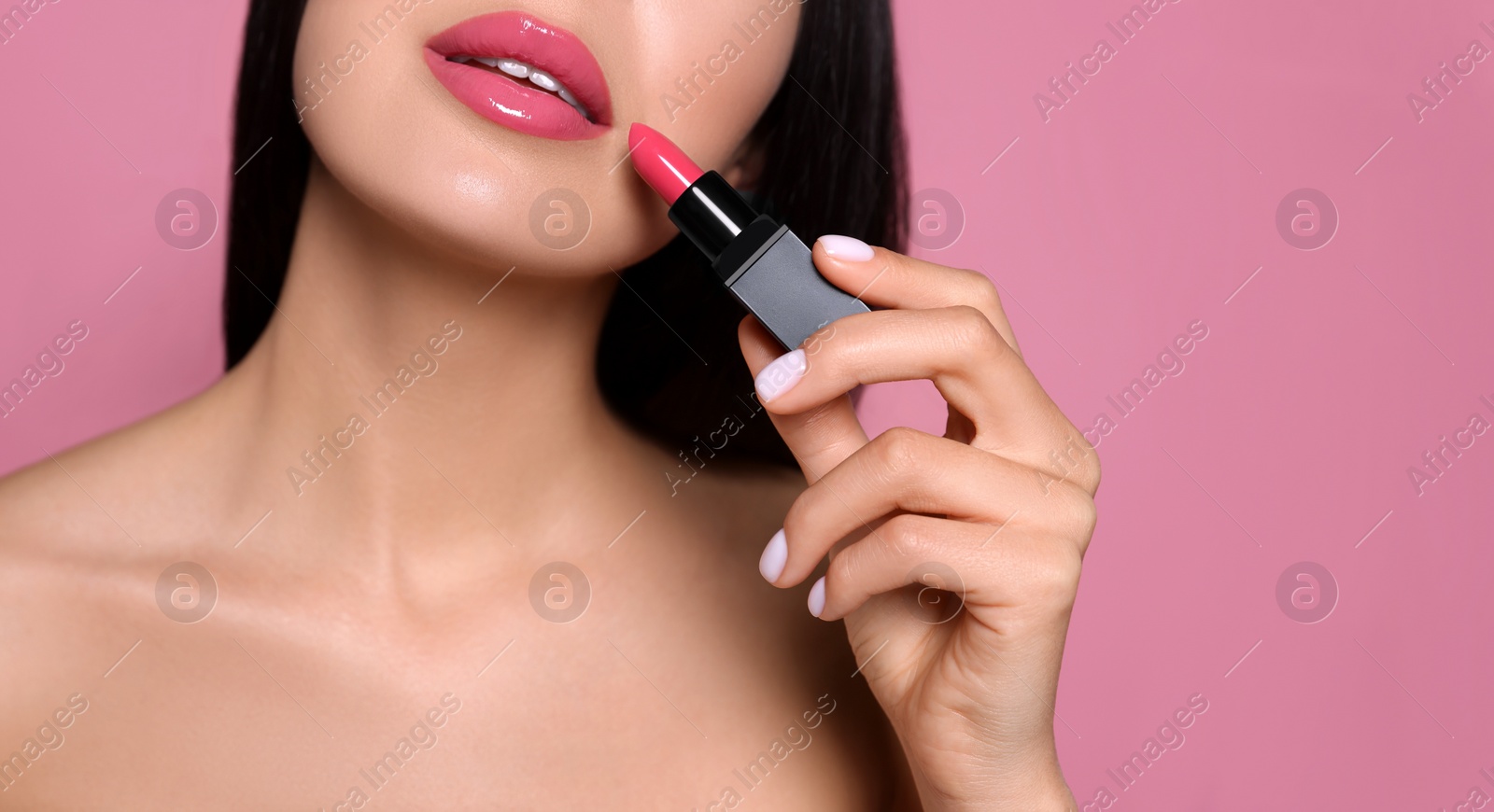 Image of Young woman with beautiful makeup holding glossy lipstick on pink background, closeup