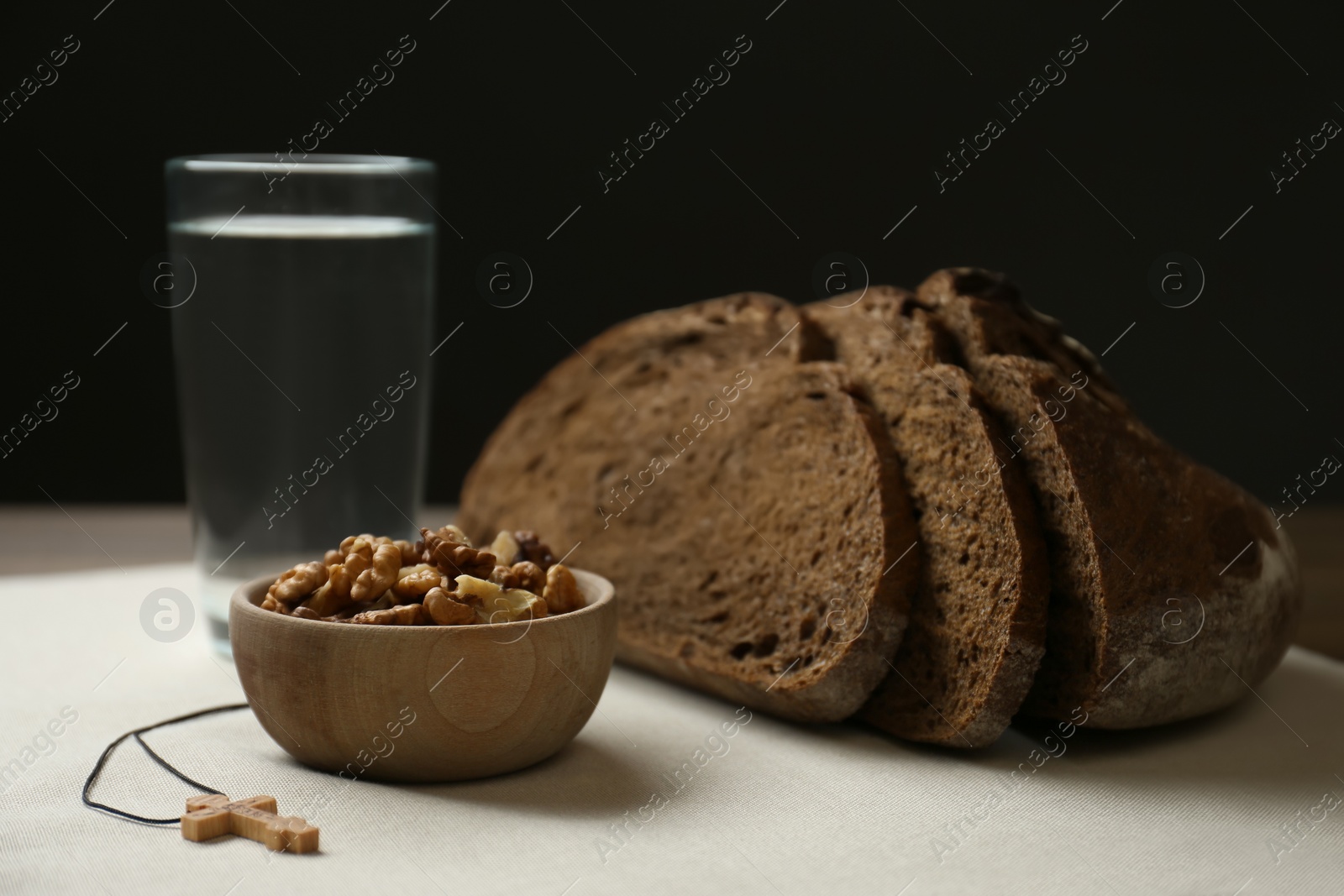 Photo of Bread, walnuts, water and crucifix on table. Great Lent season