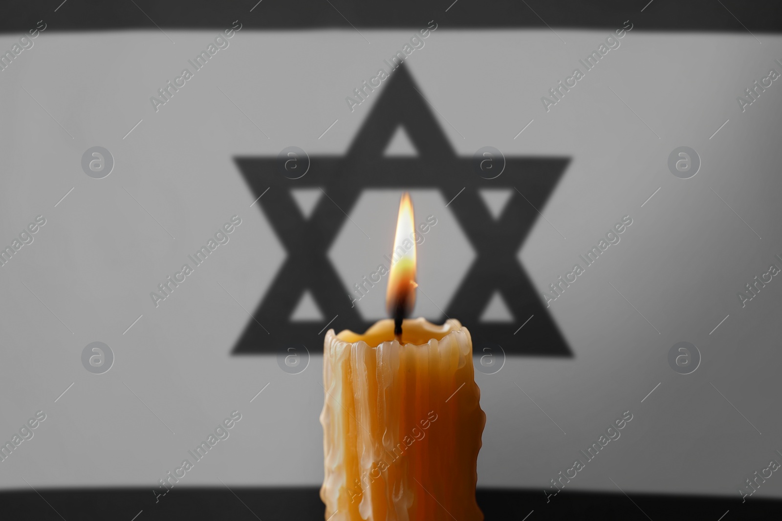 Image of Burning candle against flag of Israel, closeup