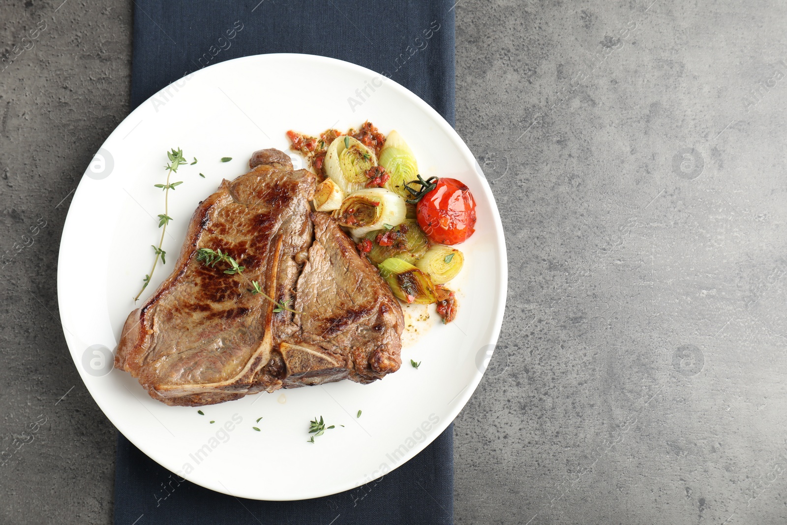 Photo of Delicious fried beef meat and vegetables on grey table, top view. Space for text