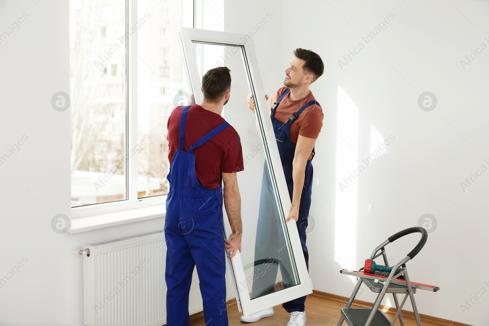 Photo of Construction workers installing plastic window in house