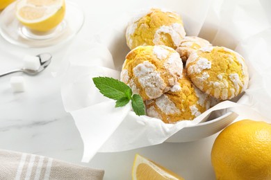 Photo of Tasty homemade lemon cookies with fresh fruit and mint on white marble table