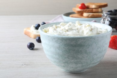 Photo of Tasty cream cheese and fresh berries on white wooden table. Space for text