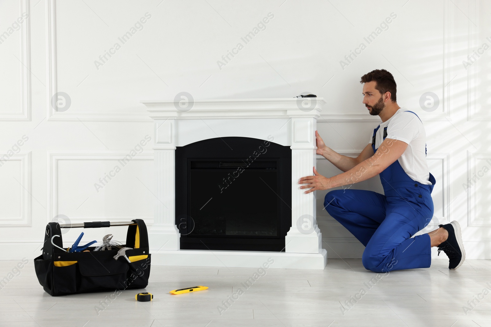 Photo of Professional technician installing electric fireplace in room