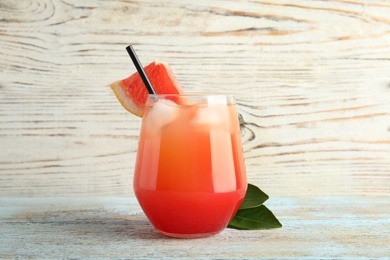 Glass of grapefruit cocktail on wooden table