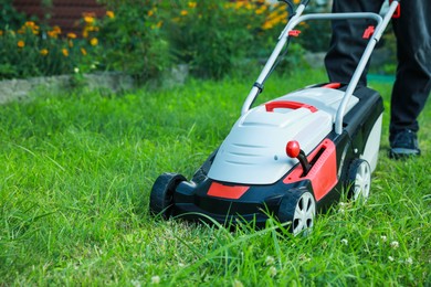 Man cutting grass with lawn mower in garden, closeup. Space for text