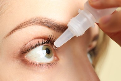 Photo of Young woman using eye drops on light background, closeup