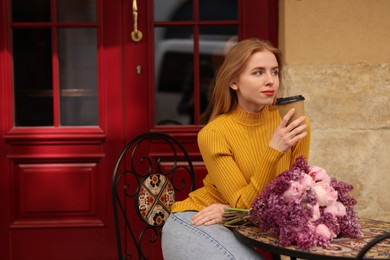 Beautiful woman with bouquet of spring flowers and coffee in outdoor cafe, space for text