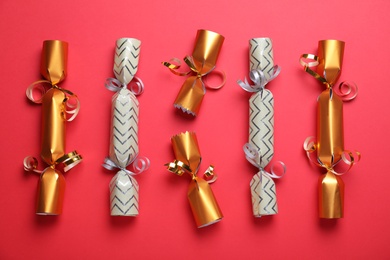 Photo of Bright Christmas crackers on red background, flat lay
