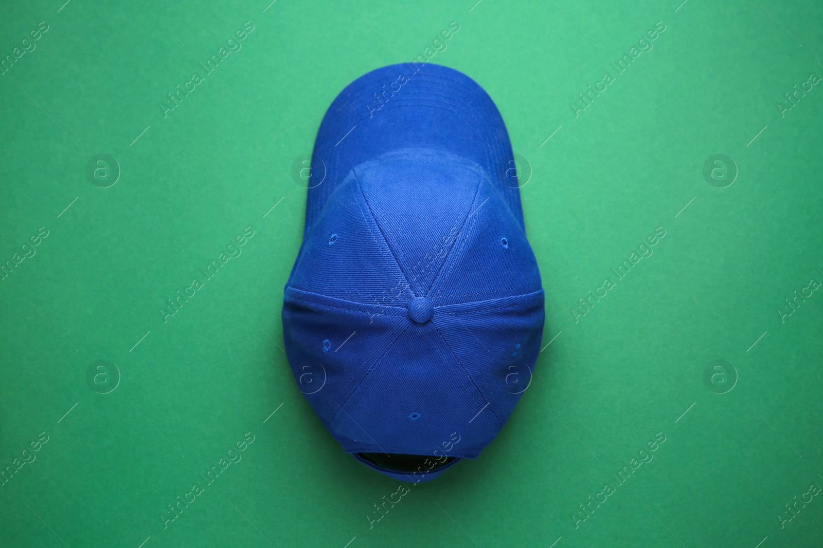 Photo of Stylish blue baseball cap on green background, top view