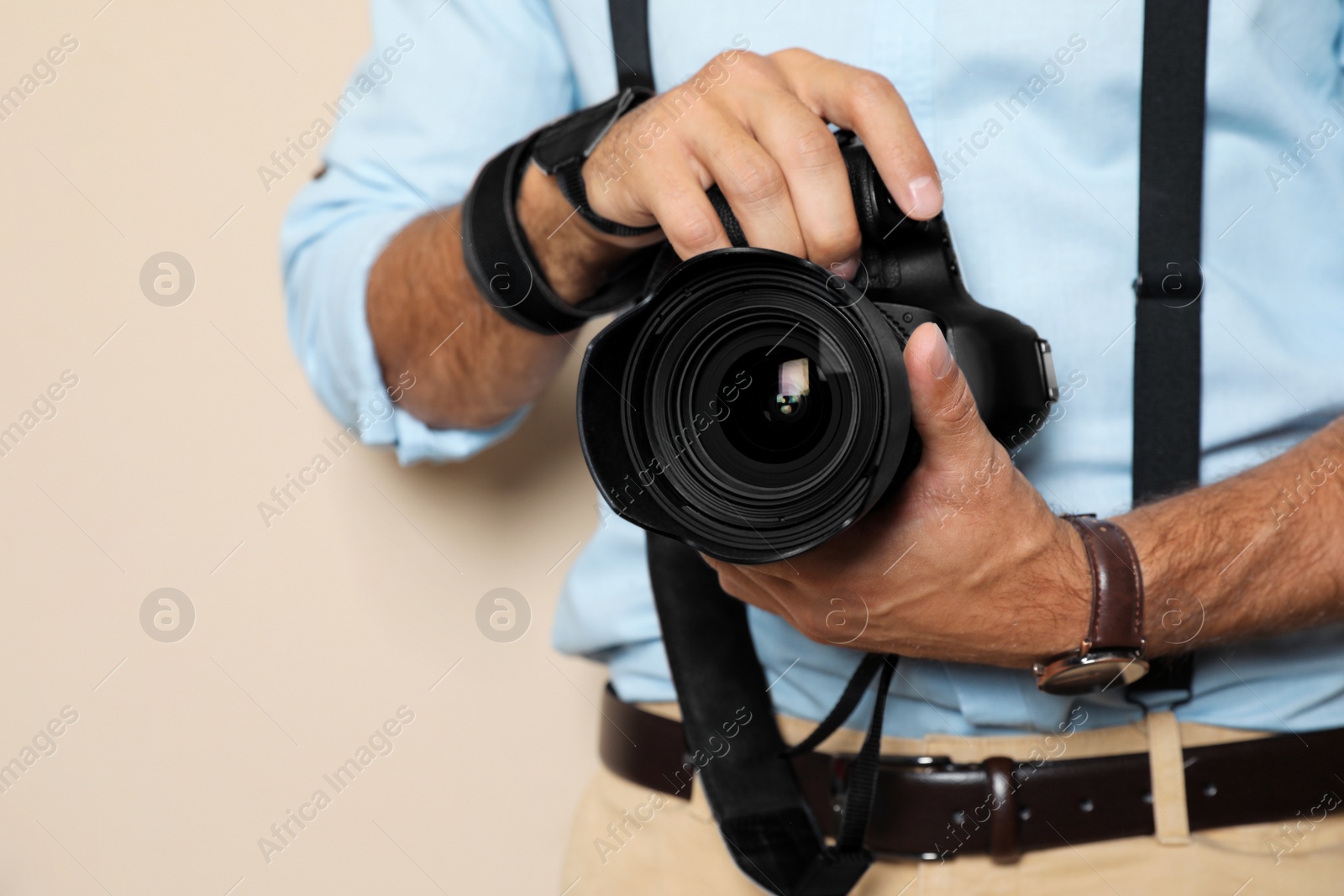 Photo of Professional photographer working on beige background in studio, closeup