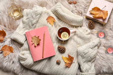 Photo of Flat lay composition with book, cup of tea and warm sweater on fuzzy rug