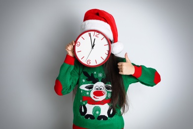 Girl in Santa hat with clock on white background. Christmas countdown