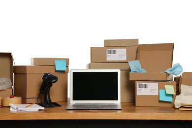 Photo of Parcels, laptop and barcode scanner on wooden table against white background. Online store