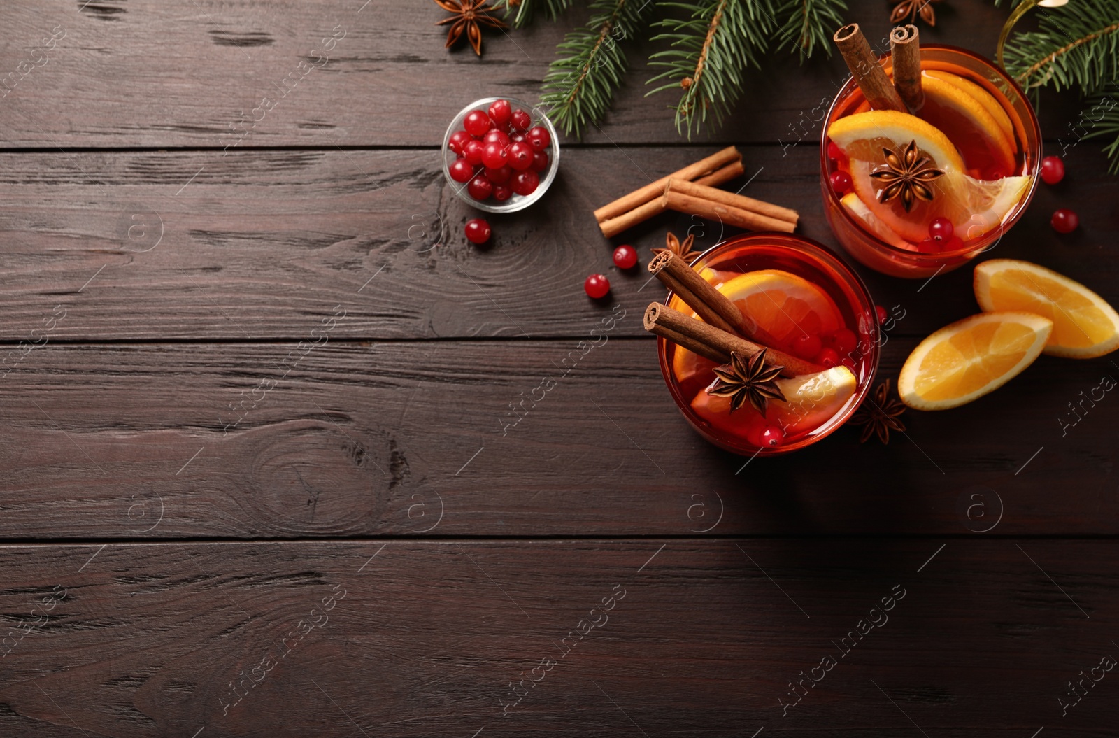 Photo of Delicious punch drink with cranberries, orange and spices on wooden table. flat lay. Space for text