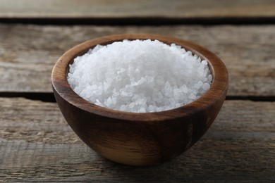 Photo of Organic salt in bowl on wooden table, closeup