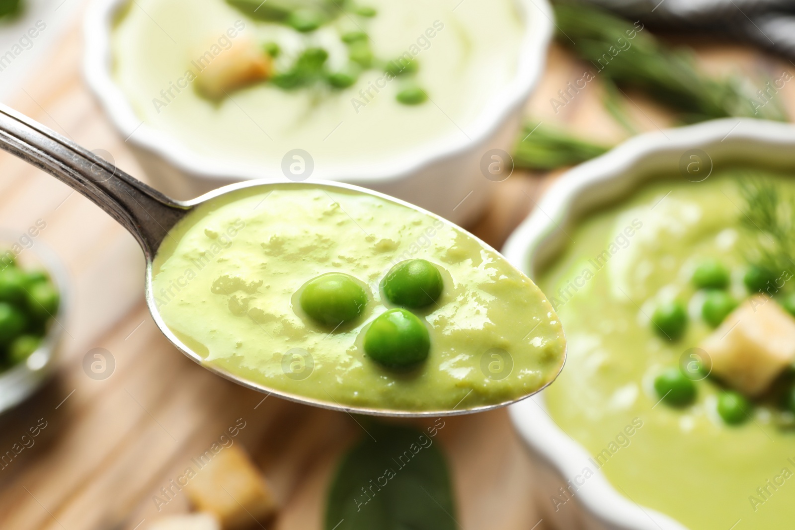 Photo of Spoon with fresh vegetable detox soup made of green peas on blurred background, closeup