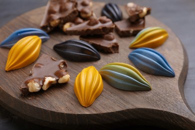 Photo of Tasty chocolate candies on wooden board, closeup