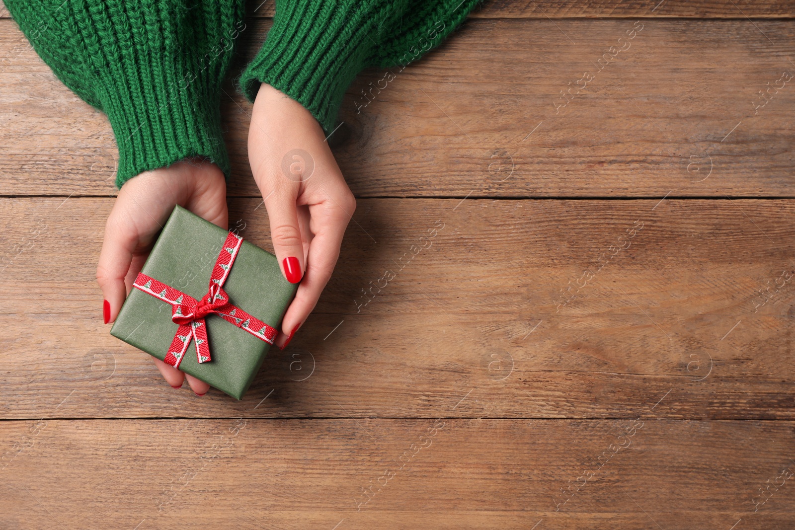 Photo of Christmas present. Woman with gift box at wooden table, top view. Space for text