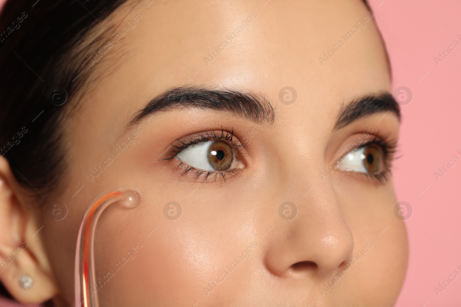 Photo of Woman using high frequency darsonval device on pink background, closeup