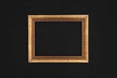 Photo of Gold painted frame on black background, top view with space for text