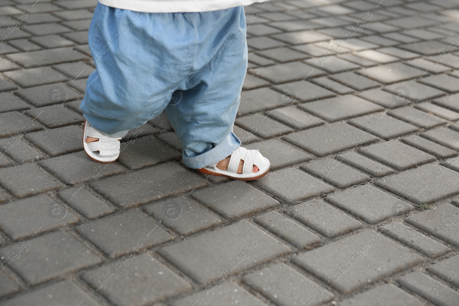 Photo of First steps. Baby learning to walk outdoors, closeup. Space for text