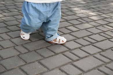 Photo of First steps. Baby learning to walk outdoors, closeup. Space for text