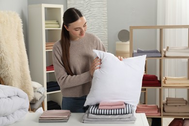 Young woman choosing pillow in home textiles store