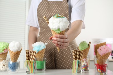 Woman holding waffle cone with cotton candy indoors, closeup