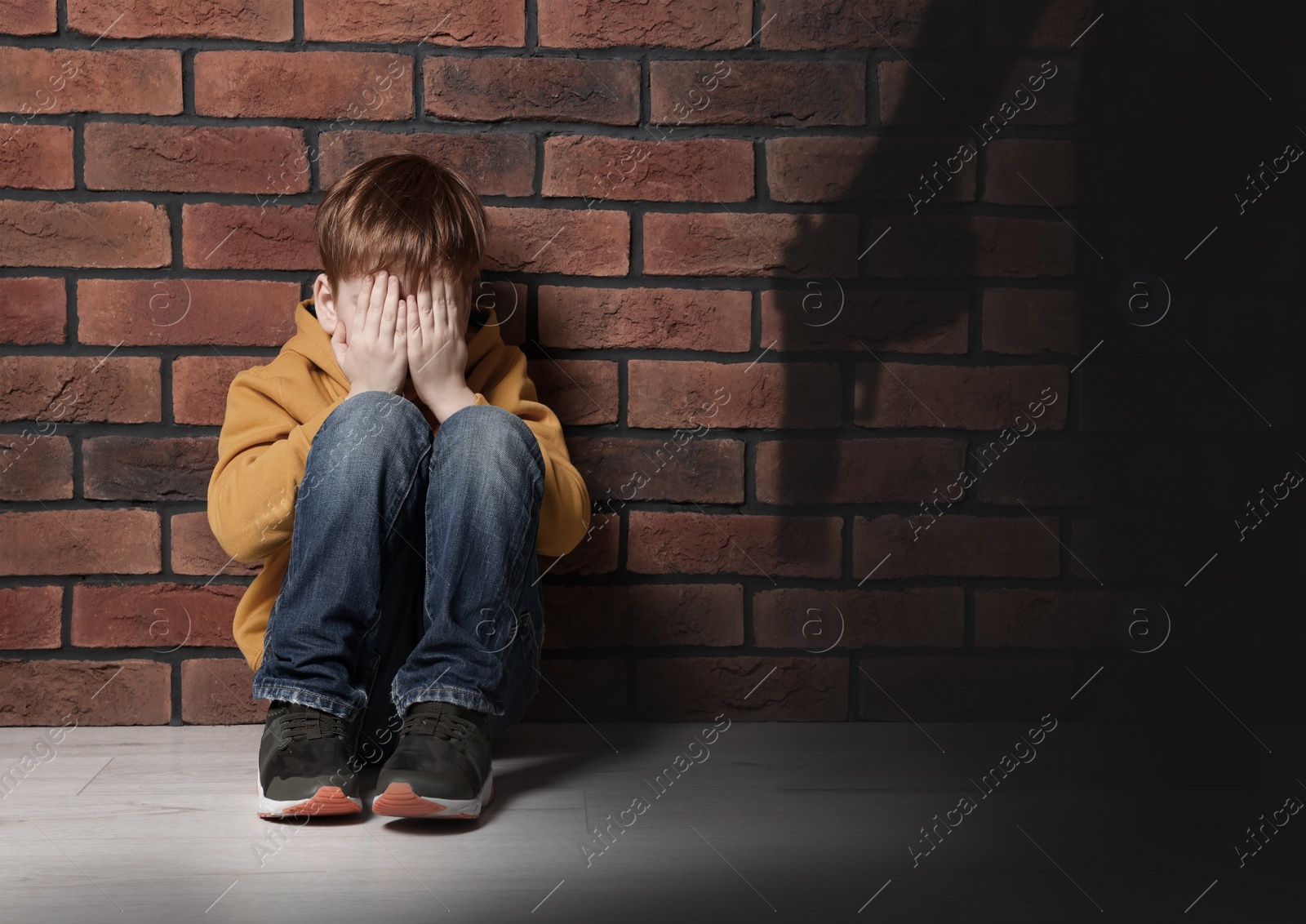 Image of School shooting. Scared little boy and shadow of man with gun indoors