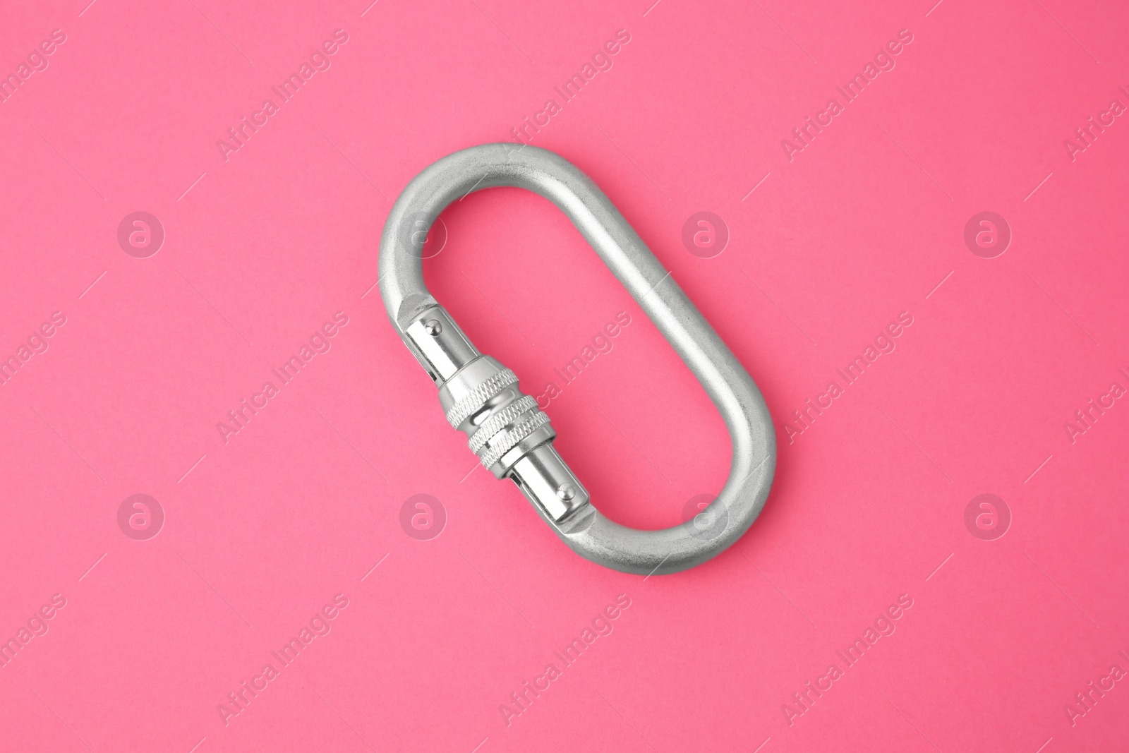 Photo of One metal carabiner on bright pink background, top view