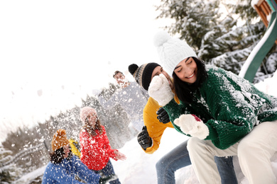 Photo of Group of friends playing snowballs outdoors. Winter vacation