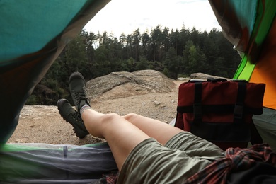 Photo of Young woman resting in camping tent, view from inside