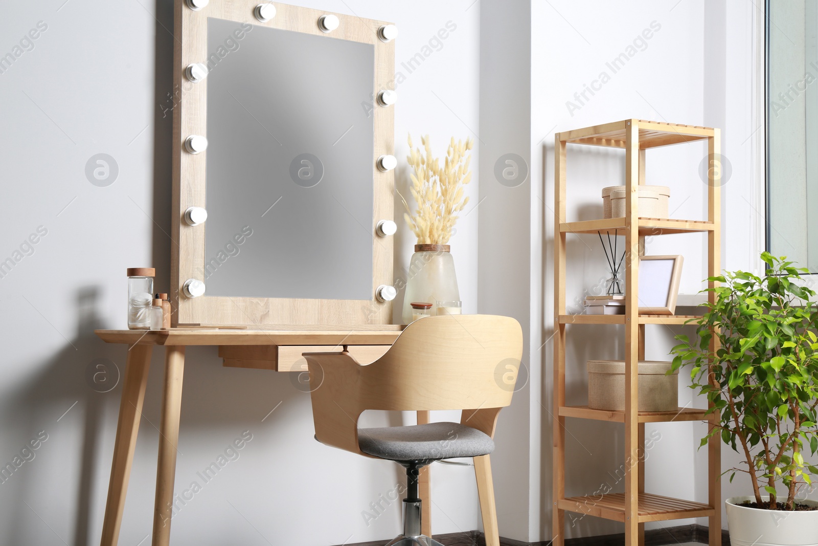 Photo of Dressing table with stylish mirror, dried reeds and other decorative elements. Interior design