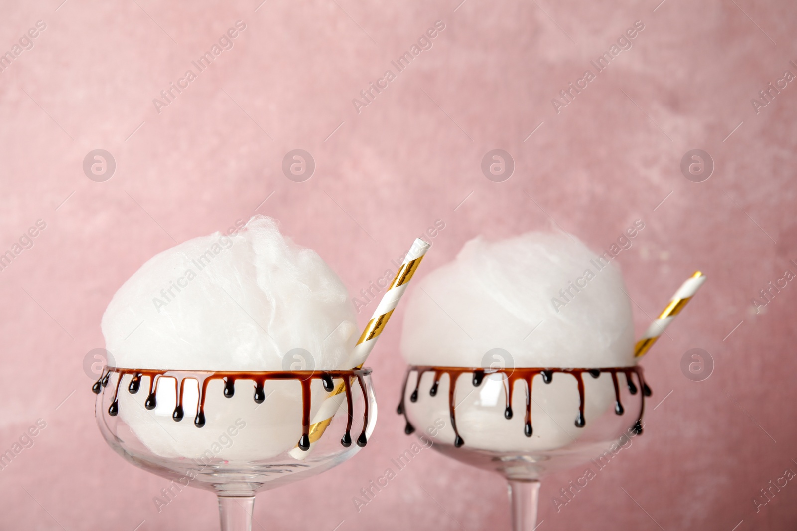 Photo of Cotton candy served in cocktail glasses on color background