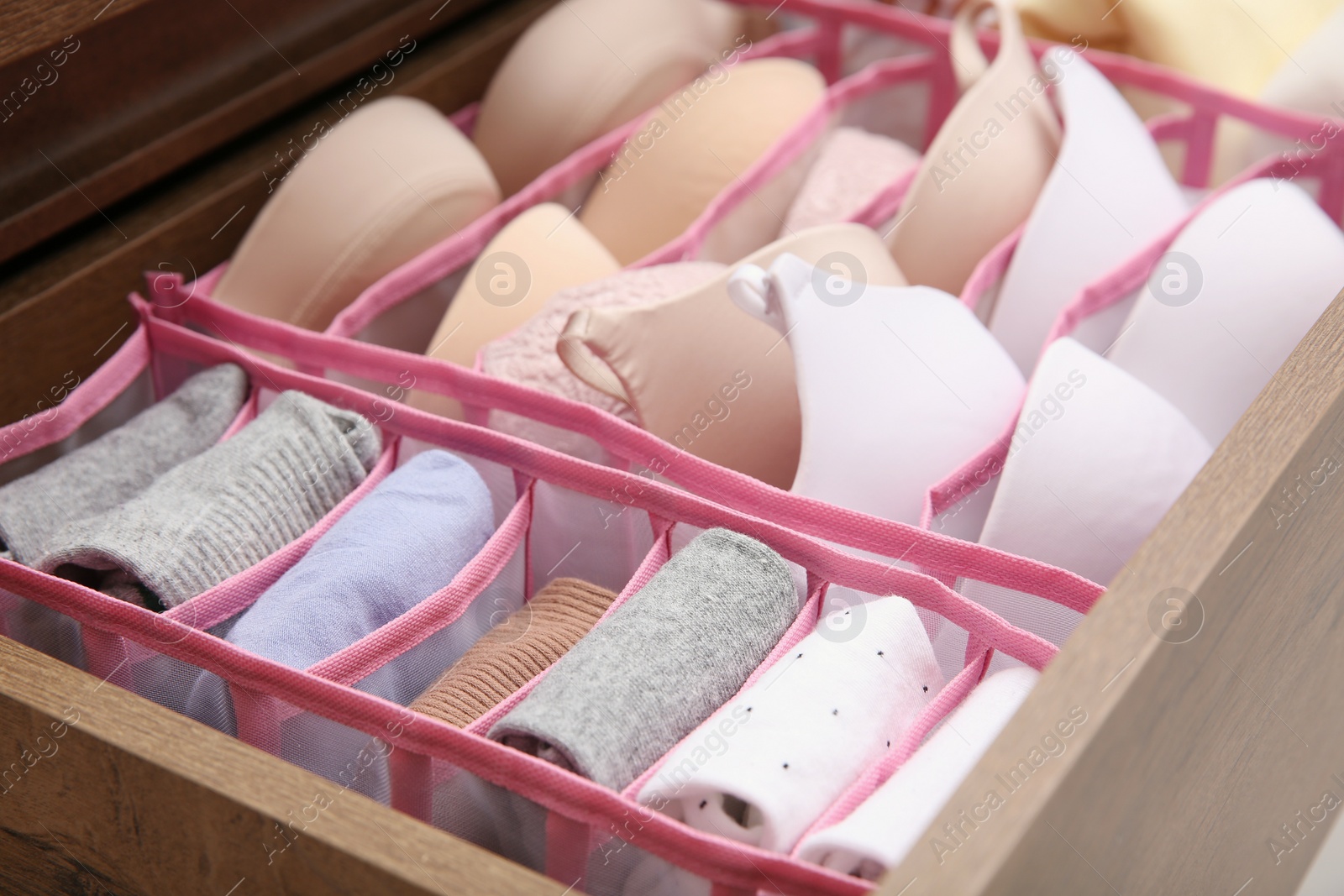 Photo of Open drawer with folded clothes and underwear indoors. Vertical storage