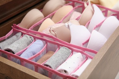 Photo of Open drawer with folded clothes and underwear indoors. Vertical storage