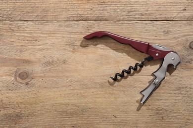 One corkscrew (sommelier knife) on wooden table, top view. Space for text