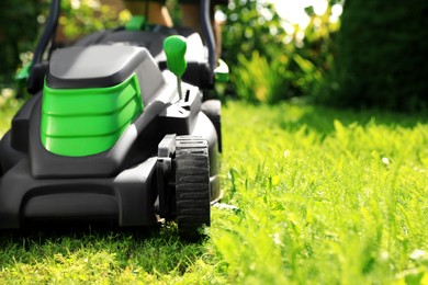 Photo of Man cutting grass with lawn mower in garden on sunny day, closeup. space for text