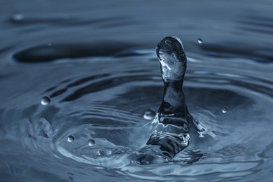 Photo of Splash of clear water with drops on dark blue background, closeup