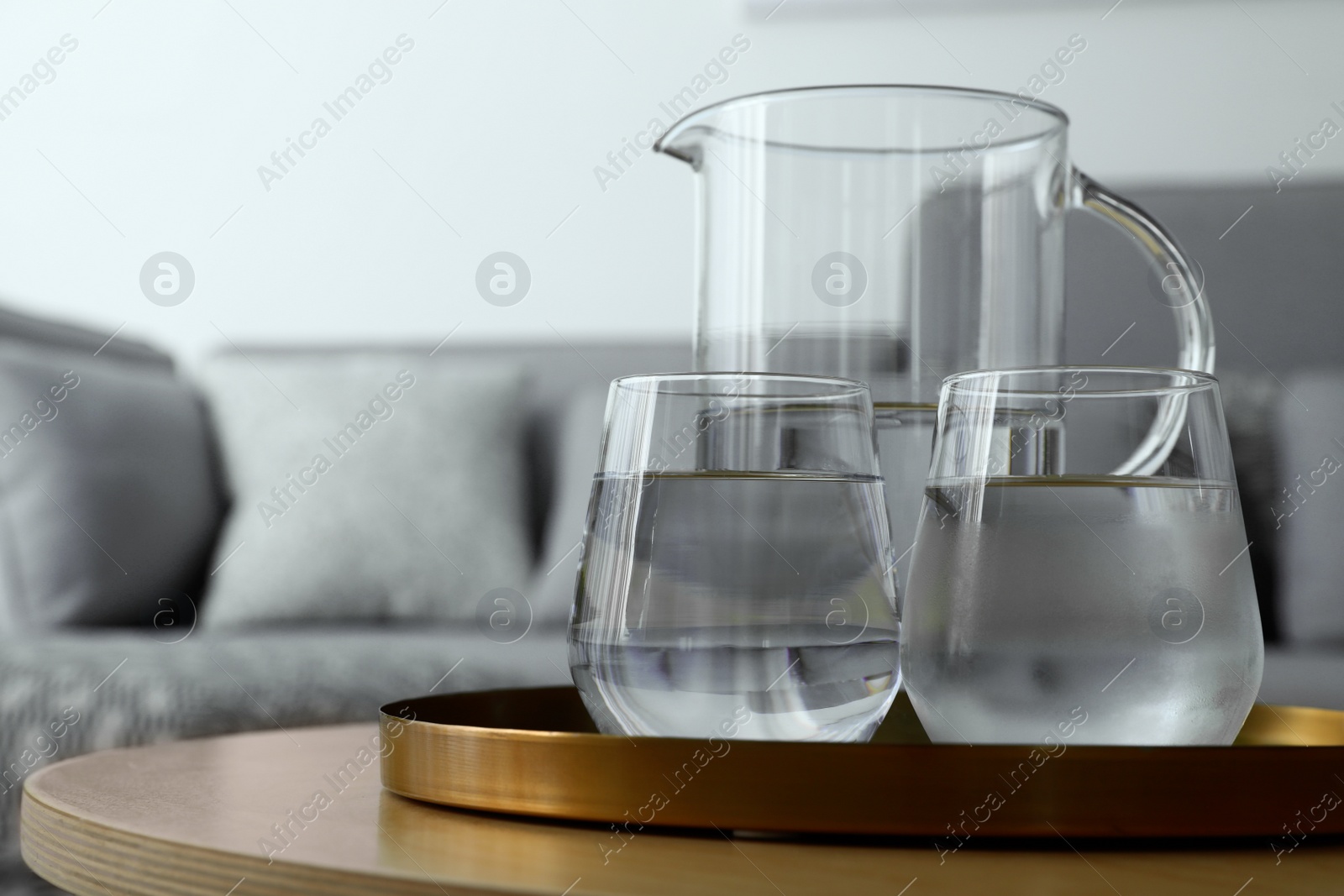 Photo of Tray with jug and glasses of water on table in room, space for text. Refreshing drink