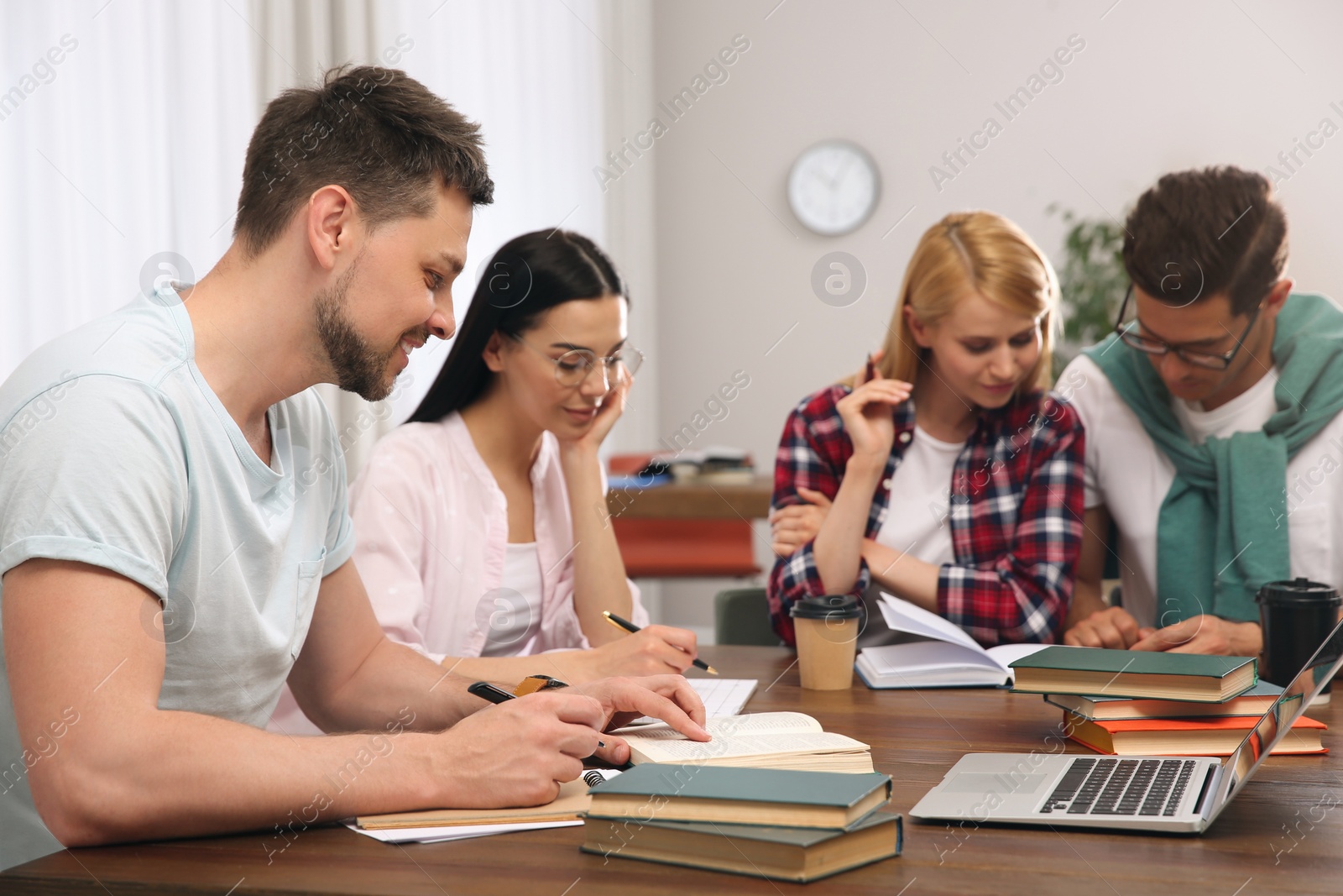 Photo of Young people discussing group project at table in library