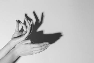 Shadow puppet. Woman making hand gesture like deer on light background, closeup with space for text. Black and white effect