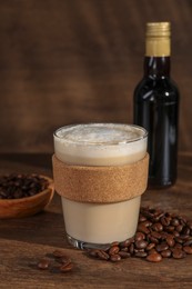 Bottle of delicious syrup, glass of coffee and beans on wooden table