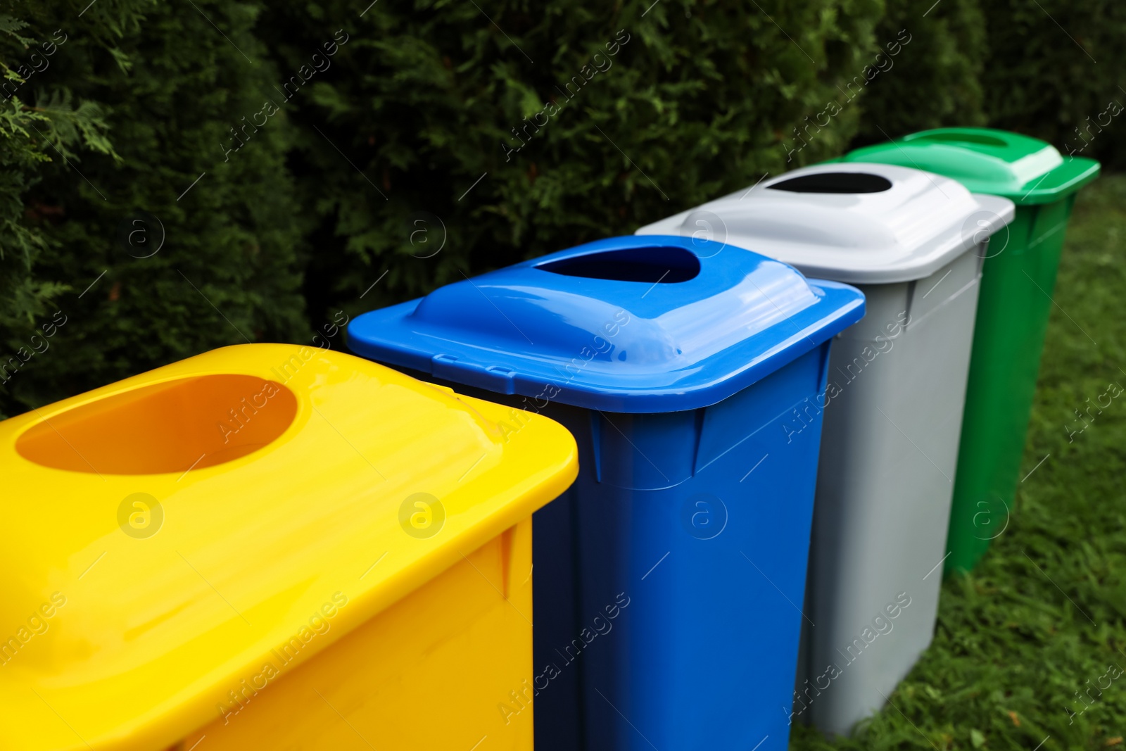 Photo of Many color recycling bins on green grass outdoors