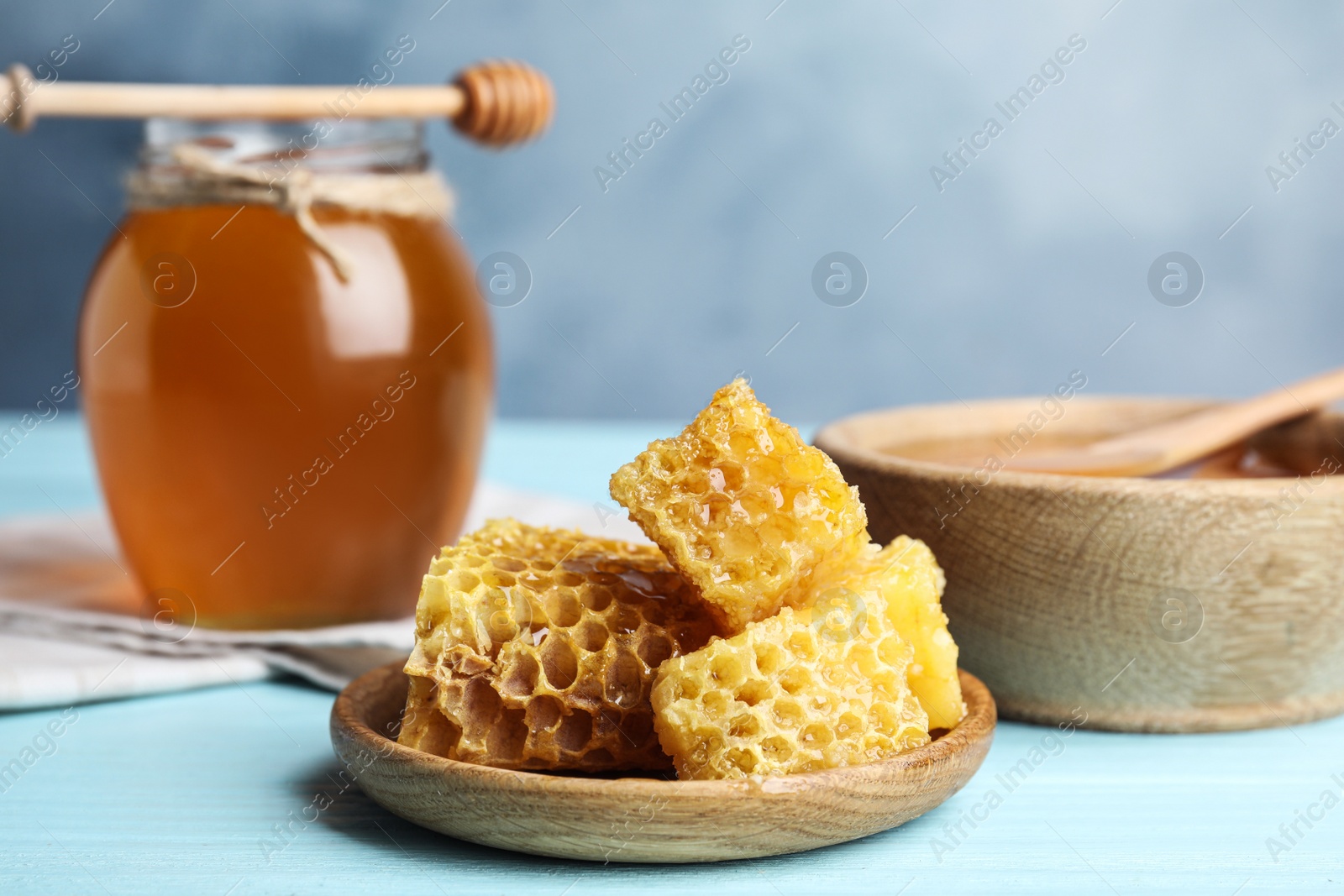 Photo of Fresh delicious honeycombs on light blue wooden table