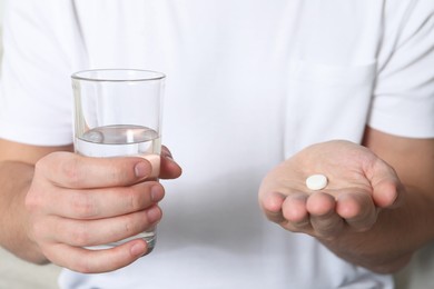 Photo of Man with glass of water and pill, closeup view